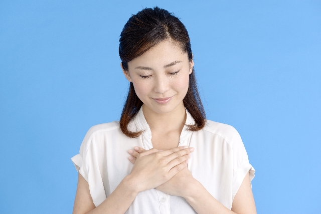 胸に手を当て安心している女性の画像