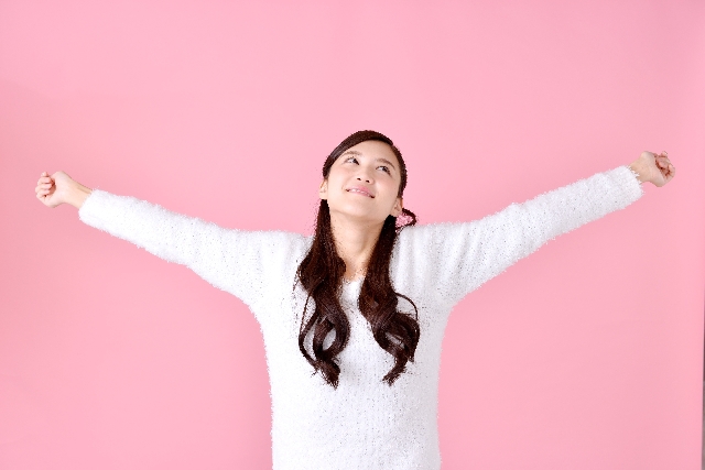 気持ちよさそうに伸びをする女性の画像