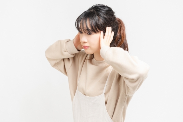 耳をふさぐ女性