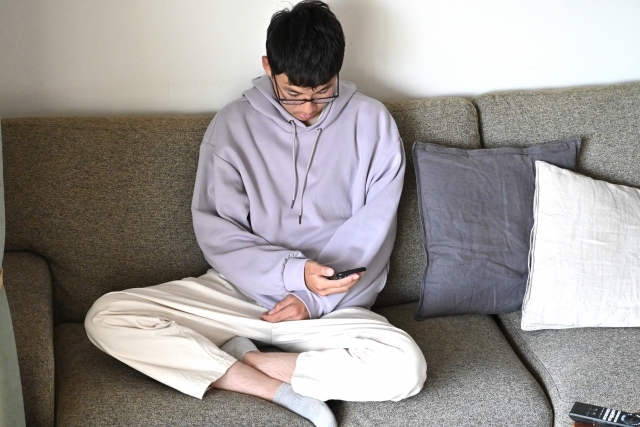 スマホをいじる男性の画像