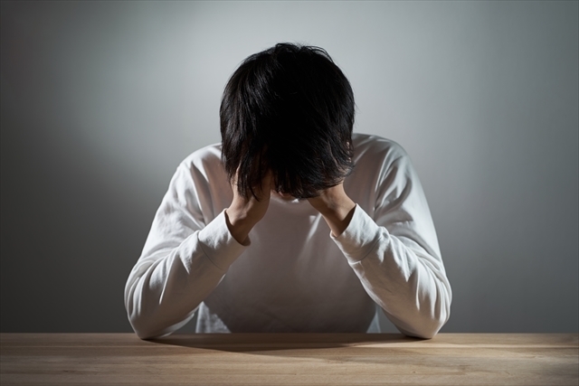 リビングで落ち込む男性の画像