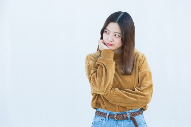 不服気な表情で立つ女性の画像