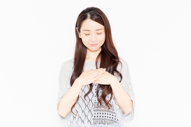 胸に手を当て目を閉じる女性の画像
