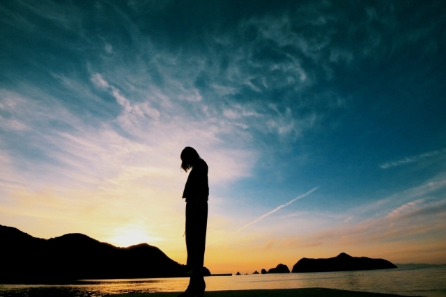 夕景のなか一人天を仰ぐ女性のシルエット