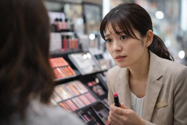 眉間にしわを寄せて化粧品を売る女性